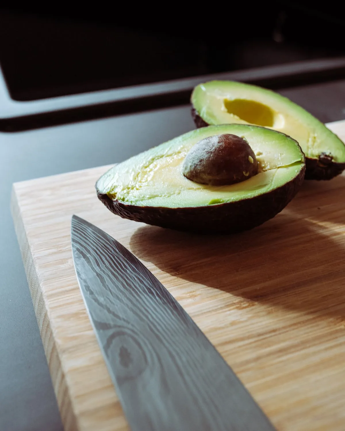 Fresh avocados cut open on a wooden board